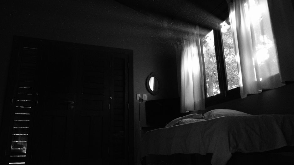 A darkened bedroom with the curtains drawn