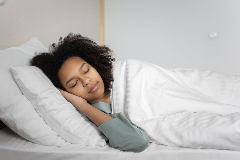 A woman asleep on white pillows in a bright bedroom