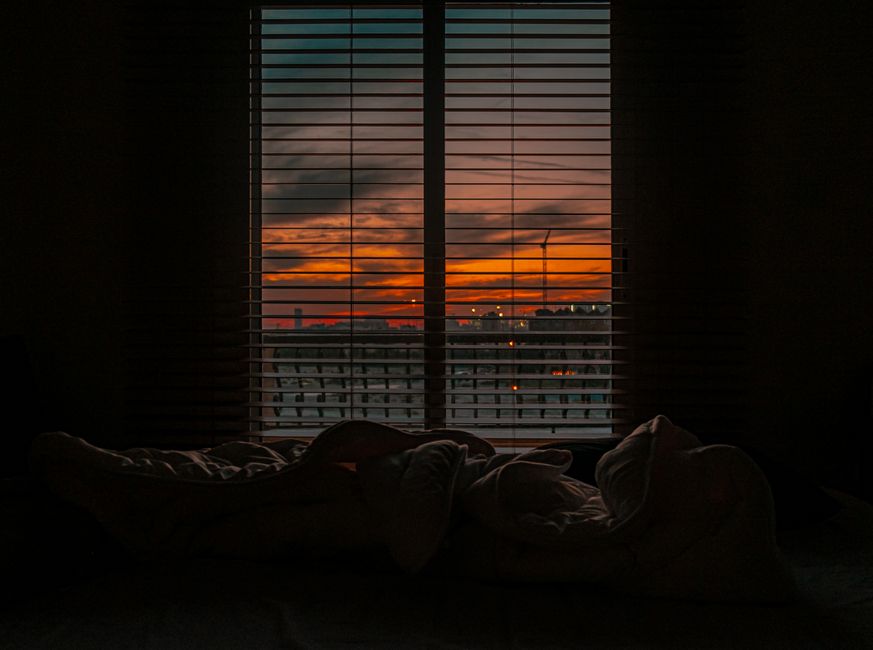 Calm dimly lit bedroom prepared for sleep with soft bedding and warm low light