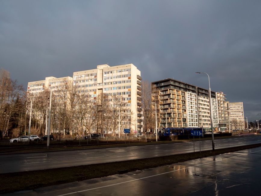Low winter sun lighting apartment buildings under a dark grey sky on a wet street